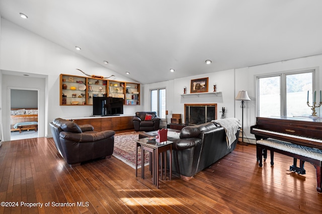 living room with lofted ceiling, baseboard heating, dark wood-type flooring, and a wealth of natural light