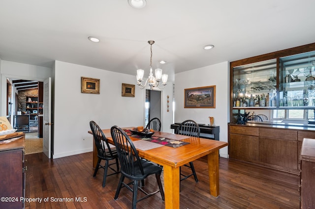 dining room with dark wood-type flooring and an inviting chandelier