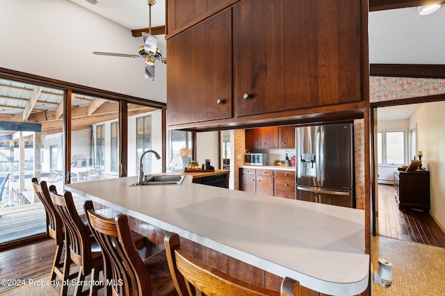 kitchen with stainless steel fridge, ceiling fan, dark hardwood / wood-style floors, vaulted ceiling with beams, and sink