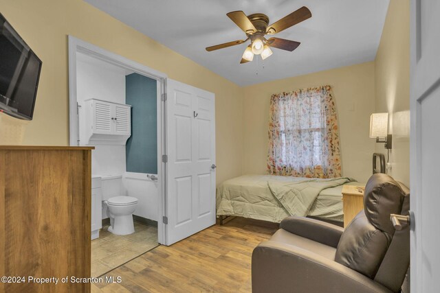 bedroom with ceiling fan, ensuite bath, and light hardwood / wood-style flooring