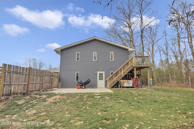 back of property with a lawn, a patio area, and a wooden deck