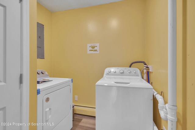 laundry area with washing machine and dryer, electric panel, a baseboard heating unit, and light wood-type flooring