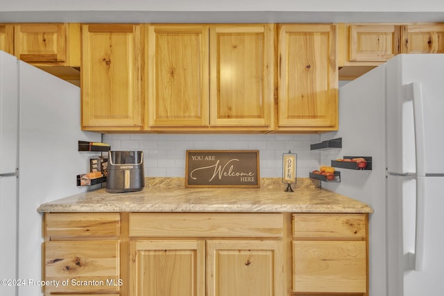 kitchen featuring light brown cabinetry, white refrigerator, and tasteful backsplash