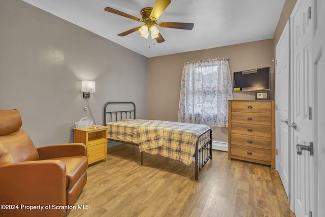 bedroom with ceiling fan, wood-type flooring, and a baseboard radiator