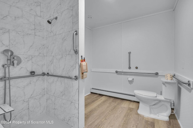 bathroom with toilet, ornamental molding, a baseboard radiator, a tile shower, and wood-type flooring