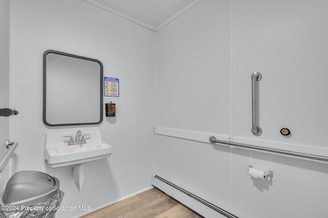 bathroom featuring sink, ornamental molding, a baseboard radiator, and hardwood / wood-style flooring