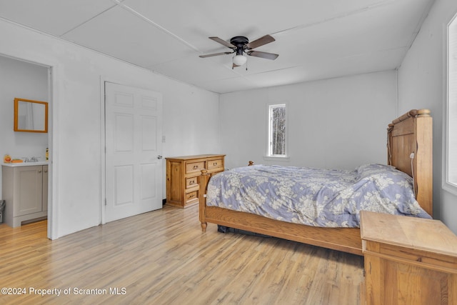 bedroom with connected bathroom, light hardwood / wood-style floors, and ceiling fan