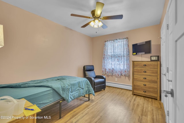 bedroom featuring ceiling fan, light hardwood / wood-style floors, and a baseboard heating unit