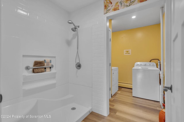 bathroom with hardwood / wood-style floors, washer and dryer, walk in shower, and a baseboard heating unit