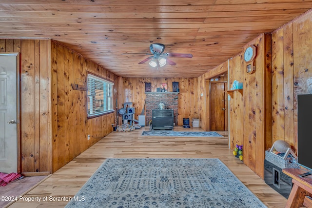 interior space with light hardwood / wood-style flooring, a wood stove, and wooden walls