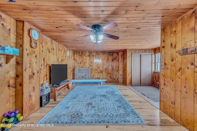 interior space featuring wooden walls, light hardwood / wood-style flooring, ceiling fan, and wooden ceiling