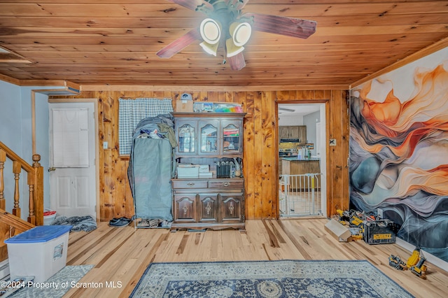 interior space with wood ceiling, ceiling fan, wooden walls, crown molding, and hardwood / wood-style flooring