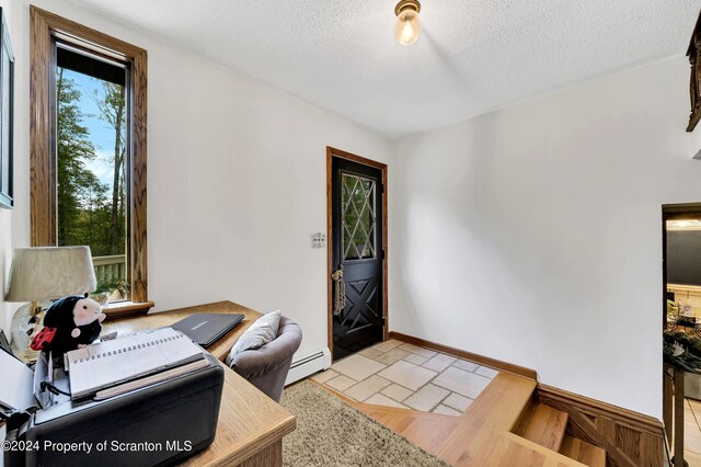 foyer entrance with a textured ceiling, baseboard heating, and light hardwood / wood-style flooring