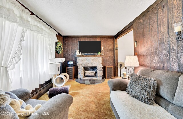 carpeted living room featuring baseboard heating, a stone fireplace, wood walls, and a textured ceiling