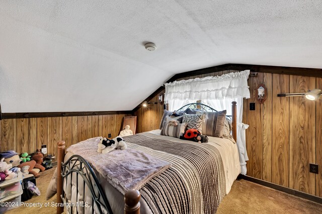 carpeted bedroom with wood walls, a textured ceiling, and vaulted ceiling