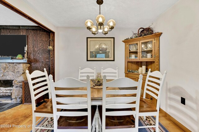 dining space with hardwood / wood-style floors, a fireplace, a textured ceiling, and a chandelier