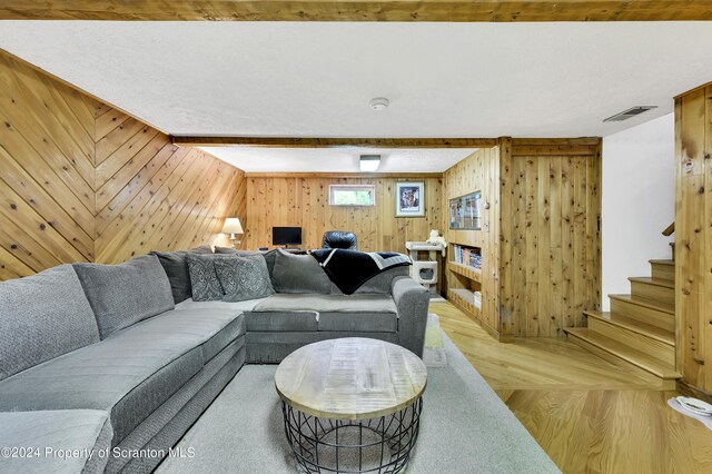 living room with hardwood / wood-style flooring, beamed ceiling, and wooden walls