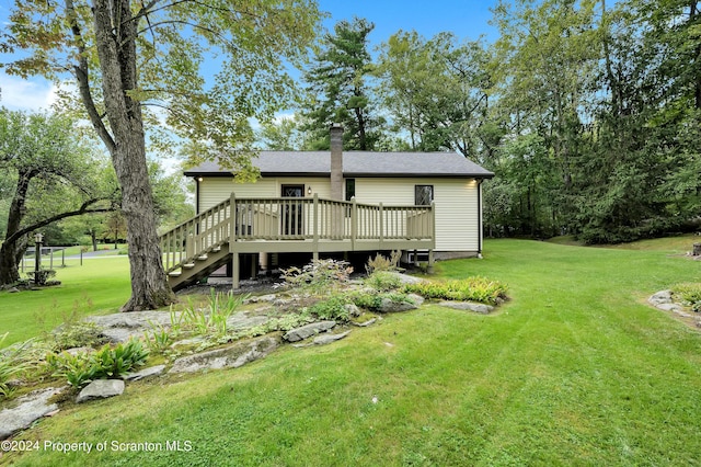 back of house featuring a lawn and a wooden deck