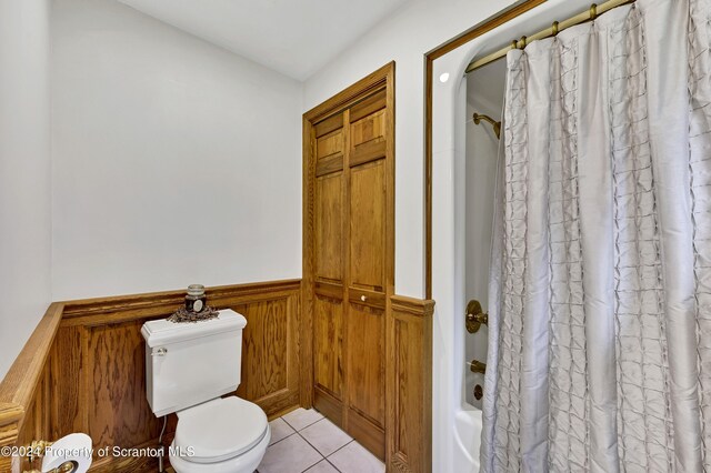 bathroom with shower / bath combo with shower curtain, wooden walls, tile patterned flooring, and toilet