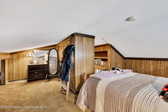 carpeted bedroom featuring a textured ceiling, wooden walls, and vaulted ceiling