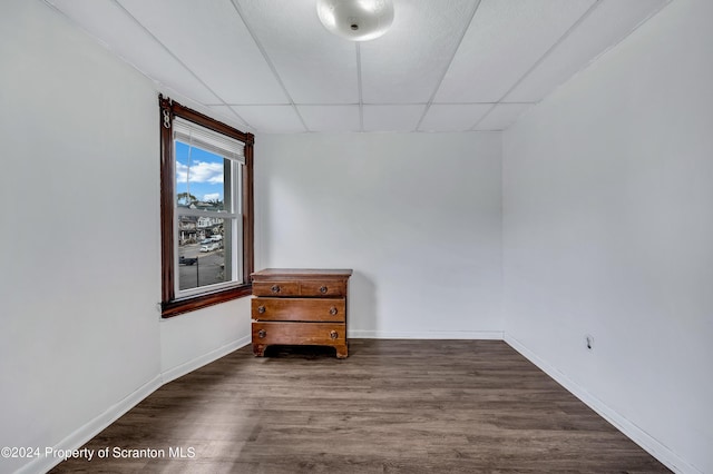 spare room with a drop ceiling and dark hardwood / wood-style floors