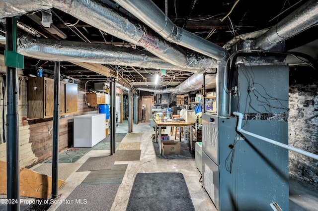 basement featuring refrigerator and heating unit