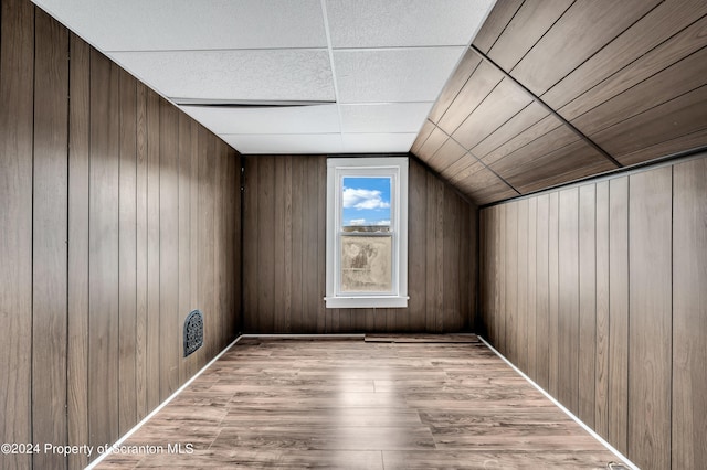 bonus room with vaulted ceiling and wood walls