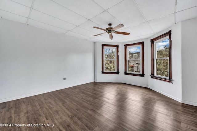 spare room with a paneled ceiling, a wealth of natural light, and dark hardwood / wood-style flooring