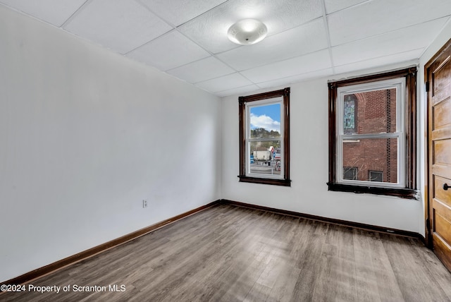 empty room with a drop ceiling and light hardwood / wood-style flooring