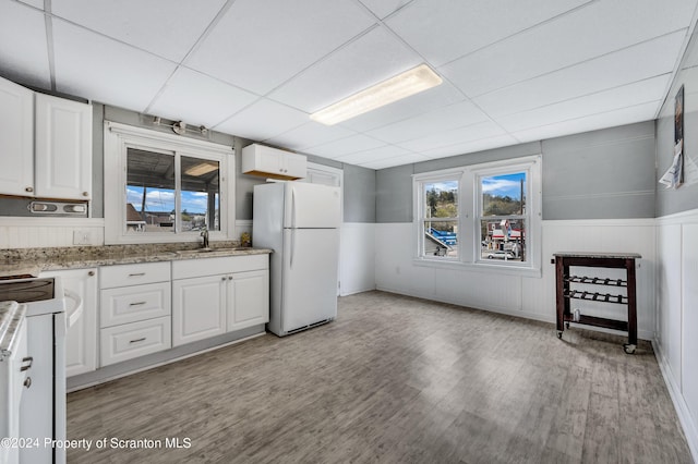 kitchen with white cabinets, a drop ceiling, white fridge, and sink