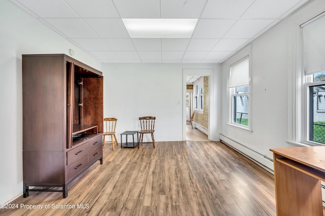 interior space featuring plenty of natural light, a drop ceiling, and a baseboard heating unit