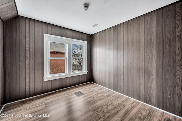 unfurnished room featuring wood walls and light hardwood / wood-style flooring