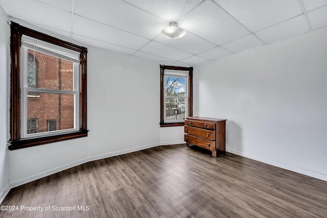 empty room featuring a drop ceiling and hardwood / wood-style flooring