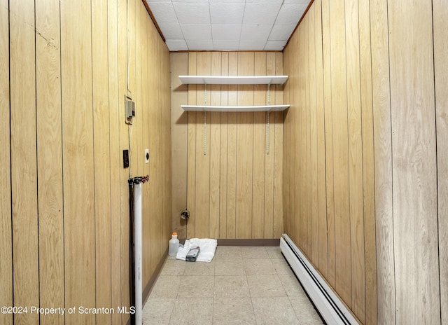 clothes washing area featuring wooden walls and a baseboard radiator