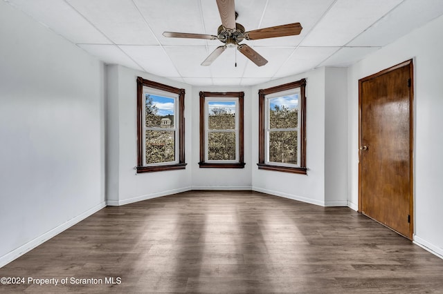 empty room featuring dark hardwood / wood-style floors, a drop ceiling, and ceiling fan