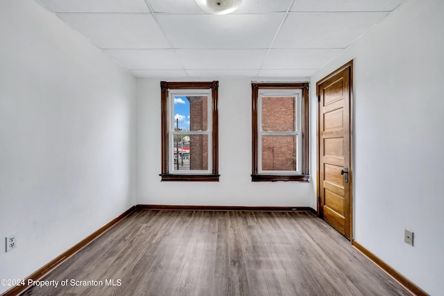 empty room with a paneled ceiling and hardwood / wood-style floors