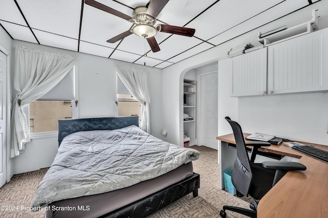 bedroom featuring a drop ceiling, light colored carpet, and ceiling fan