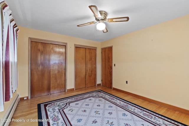 817 Miles Ave, Dickson City, PA 18447 - unfurnished bedroom featuring baseboard heating, baseboards, light wood-style flooring, and multiple closets
