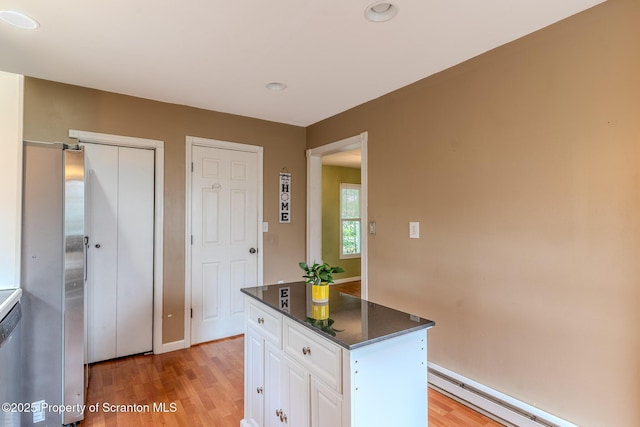 51 Plank St, Pittston, PA 18640 - kitchen with a baseboard heating unit, white cabinets, dark countertops, light wood-type flooring, and a kitchen island