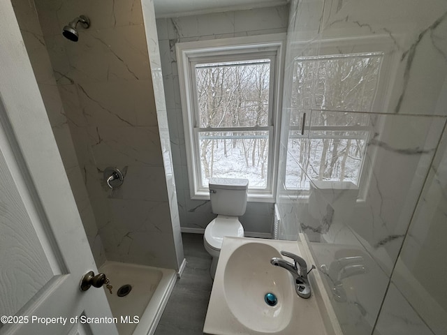 bathroom featuring a tile shower, hardwood / wood-style flooring, toilet, and sink