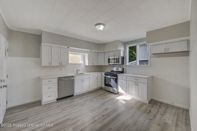 446 10th Ave, Scranton, PA 18504 - kitchen with stainless steel appliances, decorative backsplash, light wood-type flooring, white cabinetry, and light countertops