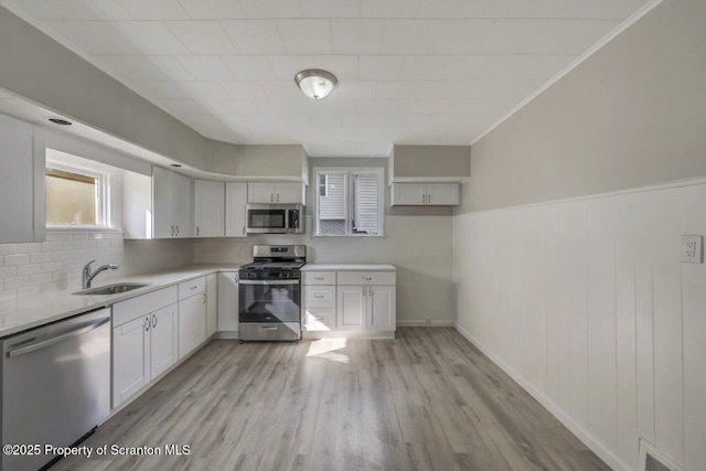 446 10th Ave, Scranton, PA 18504 - kitchen with stainless steel appliances, light countertops, tasteful backsplash, light wood-type flooring, and wainscoting