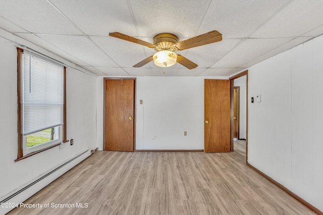 empty room with baseboard heating, a paneled ceiling, ceiling fan, and light wood-type flooring