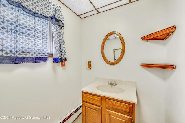 bathroom featuring a drop ceiling, vanity, and a baseboard heating unit