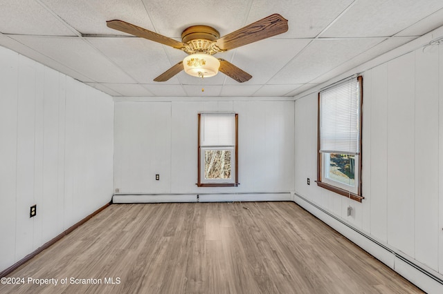 unfurnished room with a drop ceiling, light wood-type flooring, and a baseboard radiator