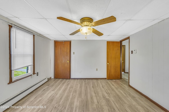 unfurnished room with a paneled ceiling, ceiling fan, light hardwood / wood-style floors, and a baseboard heating unit