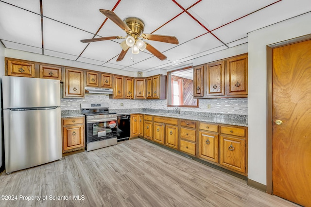 kitchen featuring a paneled ceiling, light stone counters, stainless steel appliances, ceiling fan, and light hardwood / wood-style floors