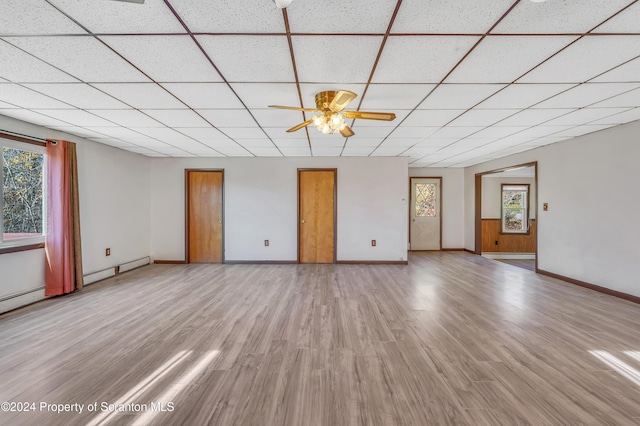 unfurnished living room with light hardwood / wood-style flooring, a drop ceiling, a healthy amount of sunlight, and ceiling fan