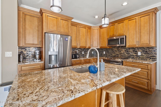 kitchen with sink, light stone counters, pendant lighting, appliances with stainless steel finishes, and ornamental molding