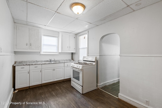 kitchen featuring white gas range, a drop ceiling, and dark wood-type flooring